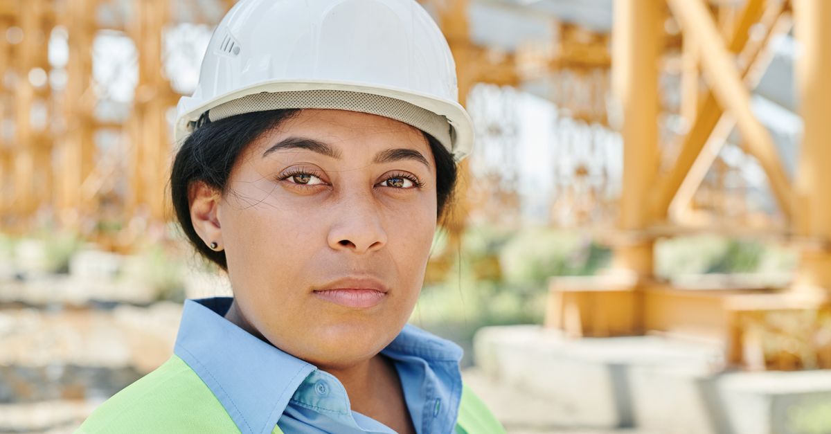 Portrait of a female engineer wearing a hard hat and safety vest on a construction site.